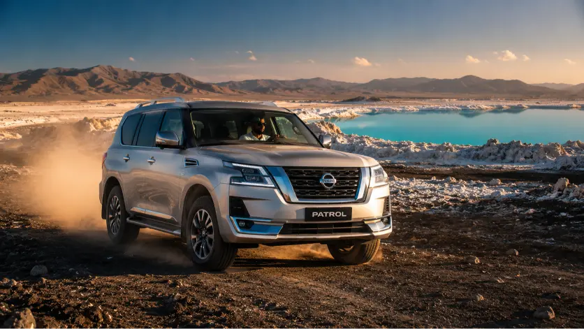 Voiture tout-terrain Djibouti — Nissan Patrol sur piste volcanique près du Lac Assal, lumière dorée, terrain basaltique
